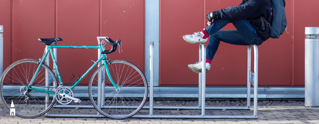 Una bicicletta e un ragazzo appoggiato ad alcune transenne